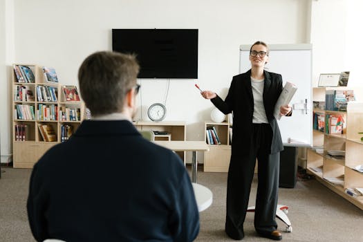 A teacher in a black blazer conducts a session with a student in a library setting.